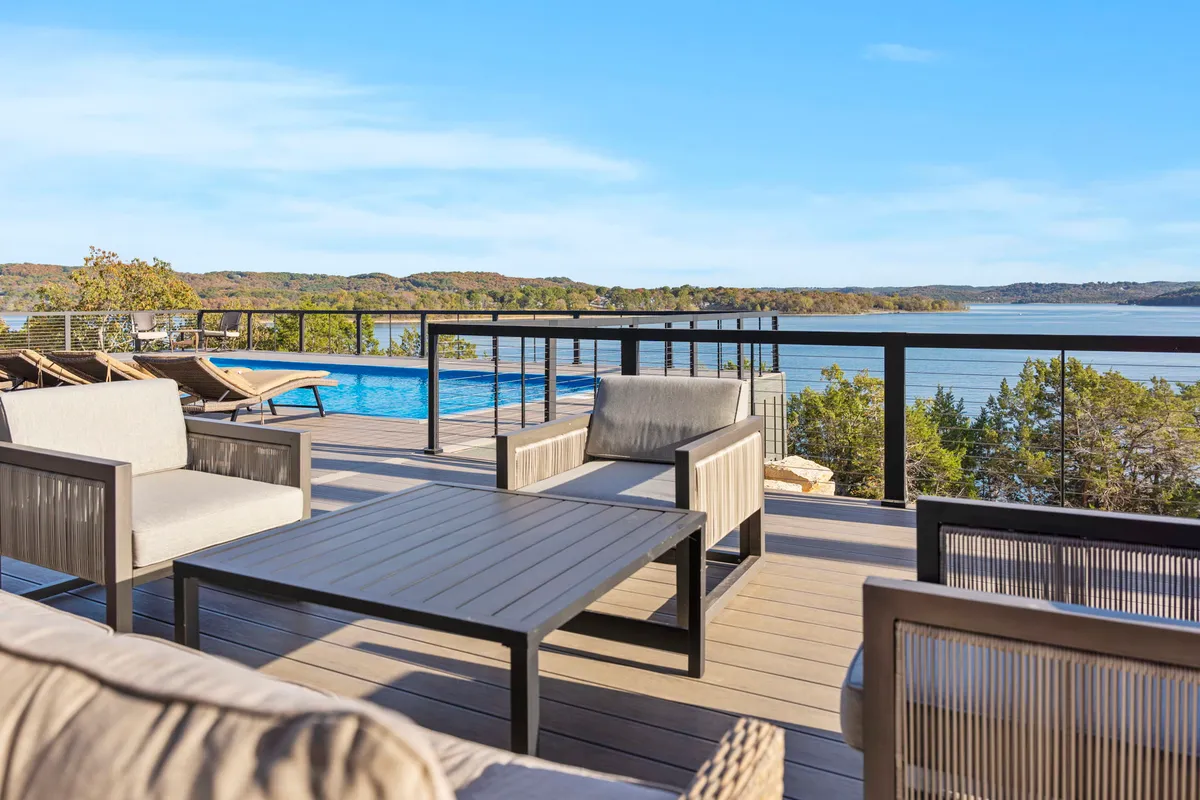 A serene scene of a swimming pool overlooking the lake, accompanied by an outdoor seating area. The tranquil setting captures moments of swimming, sunbathing, and outdoor dining with a beautiful view.