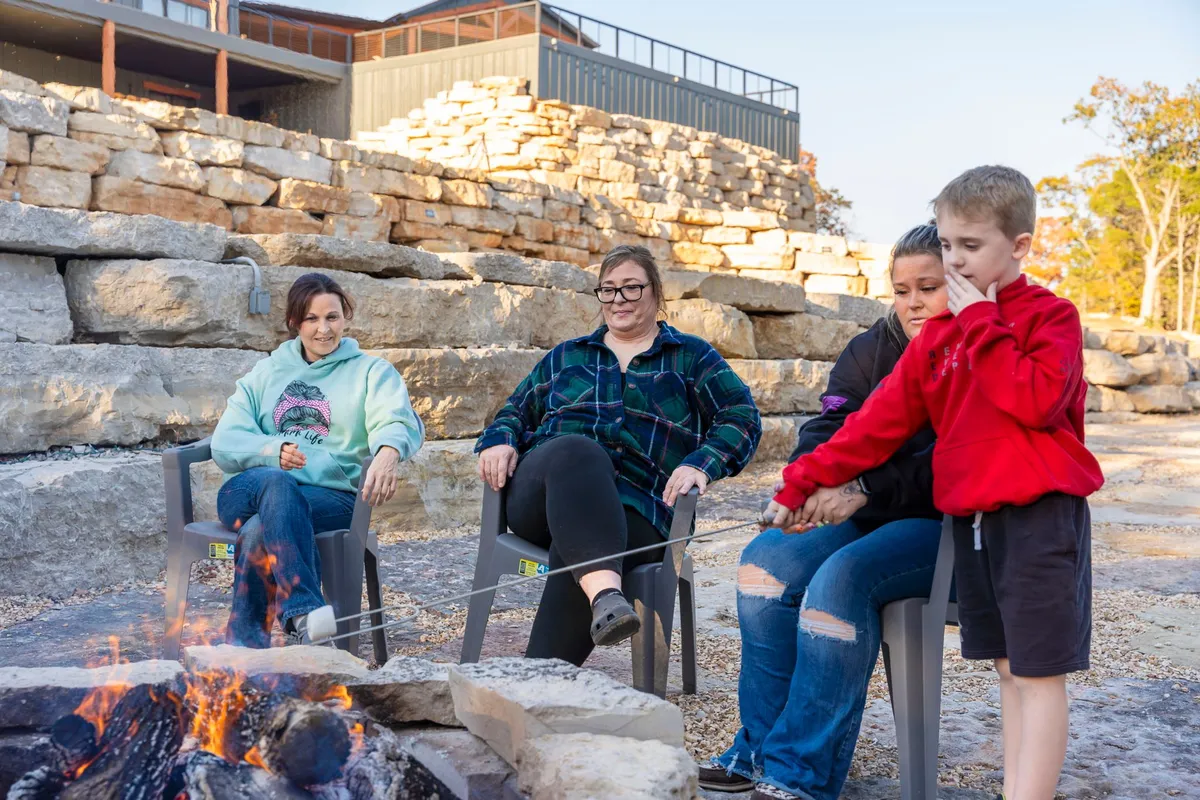 A welcoming fire pit area with people roasting marshmallows around a campfire, complete with rock seating and a cozy nighttime atmosphere. This image highlights the communal aspect of the fire pit and the fun of making s'mores together on cool evenings.