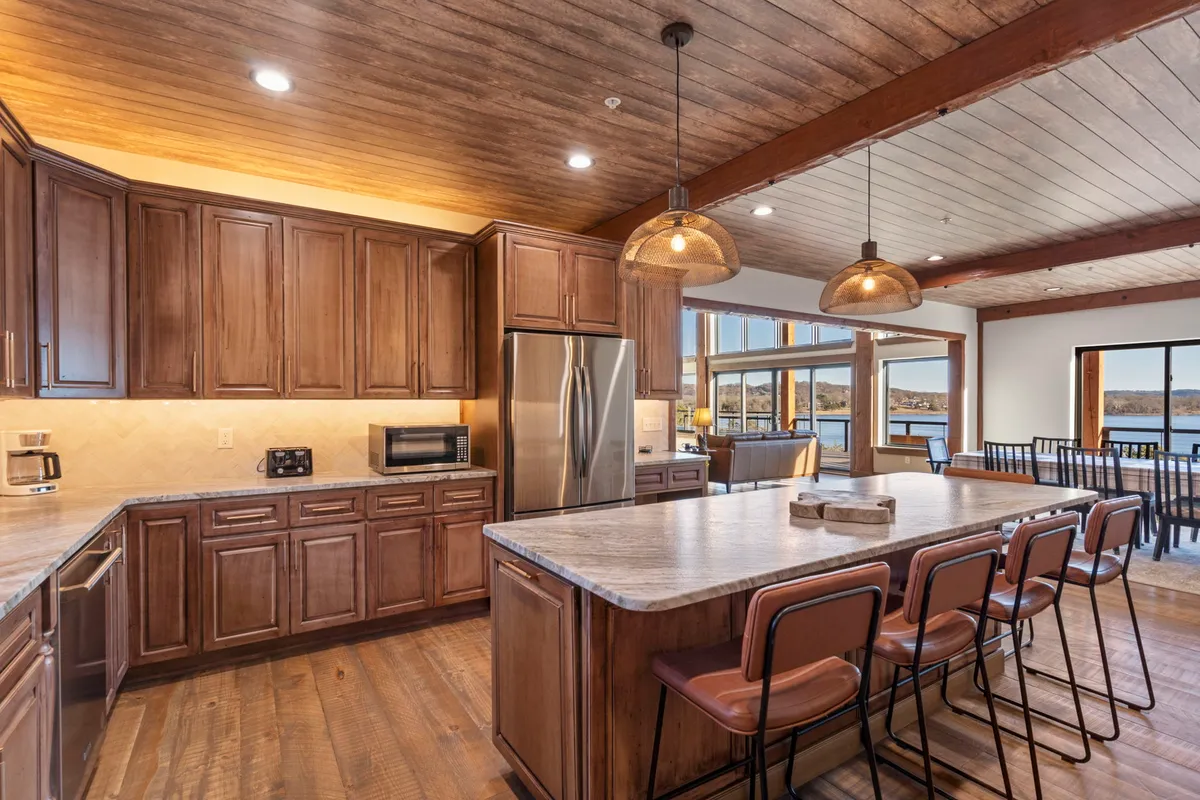 A modern, spacious kitchen featuring a large island, ample cabinetry, appliances, and expansive windows that let in natural light. The setting is perfect for preparing group feasts or casual meals while still enjoying a scenic view.
