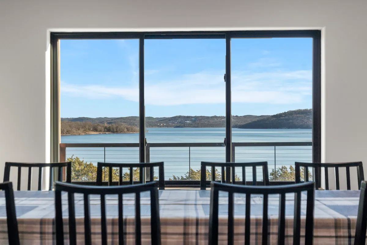 This image displays the dining area with a large table set beside a generous window offering a panoramic view of the lake. The serene atmosphere is perfect for shared meals and toasting special moments while enjoying the natural surroundings.
